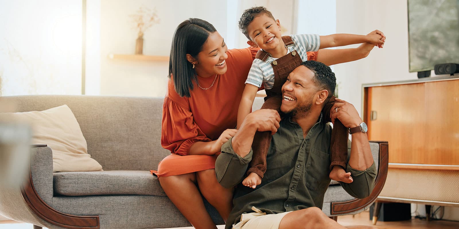 A family sitting on the couch playing with their dog.
