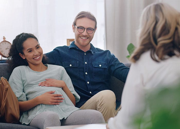 A man and woman sitting on the couch smiling.