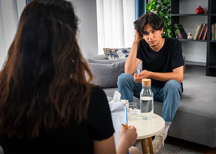 A man and woman sitting on the couch talking.