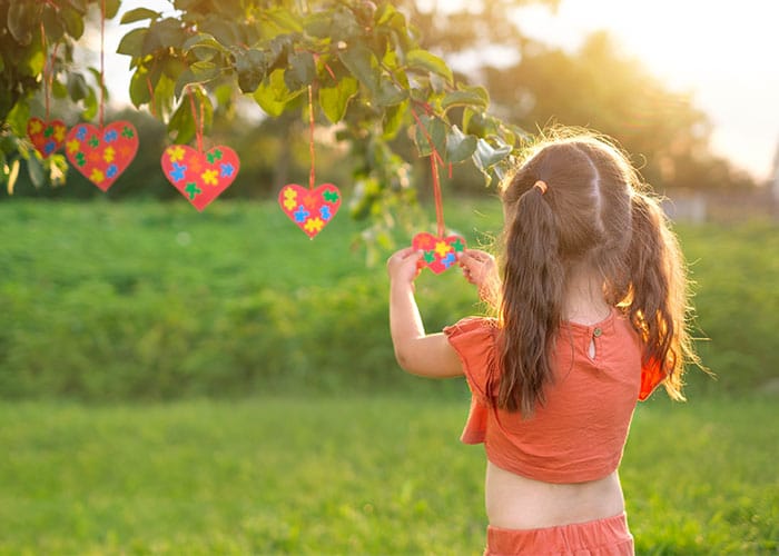 A little girl holding onto some kites in the grass