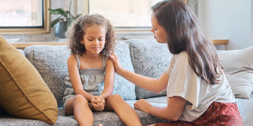 A woman is helping a child with her hair.