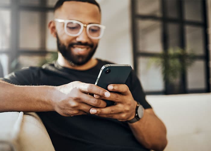 A man sitting on the couch looking at his phone.