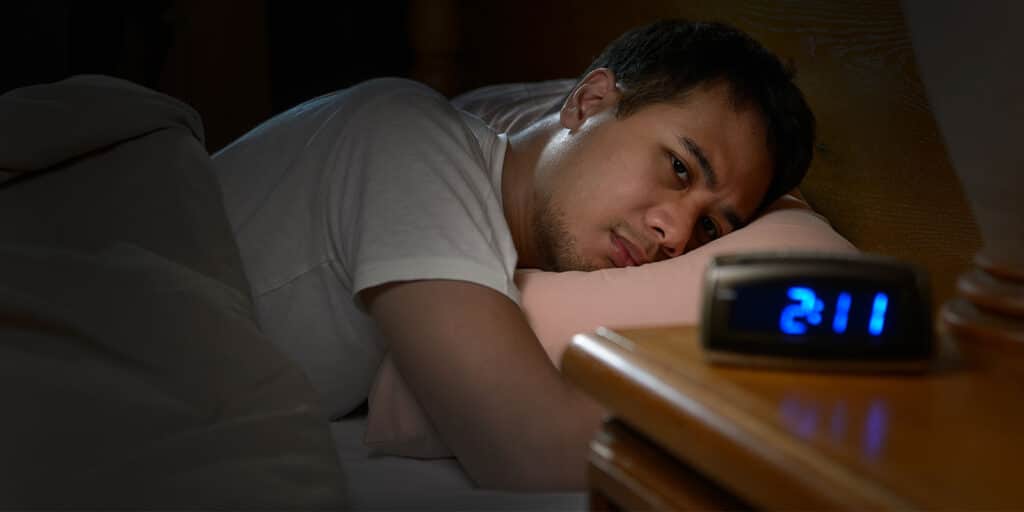 A man laying in bed with his head on the table