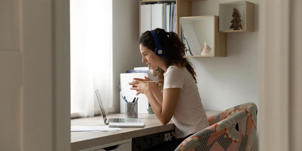 A woman sitting at her desk with headphones on.