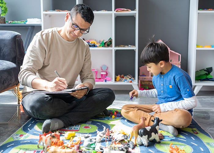 A man and boy sitting on the floor playing with toys.
