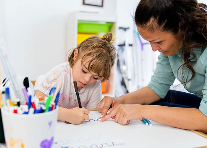 A woman and child are drawing on paper.