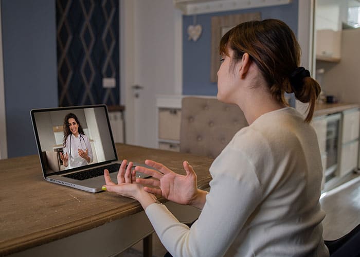 A woman sitting at a table with her laptop.