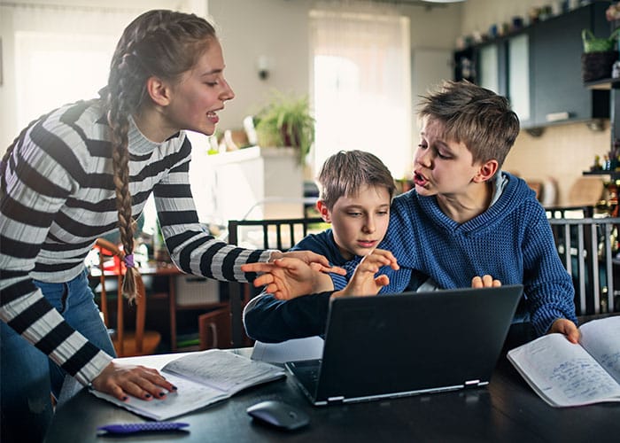 A woman and two boys are looking at a laptop.