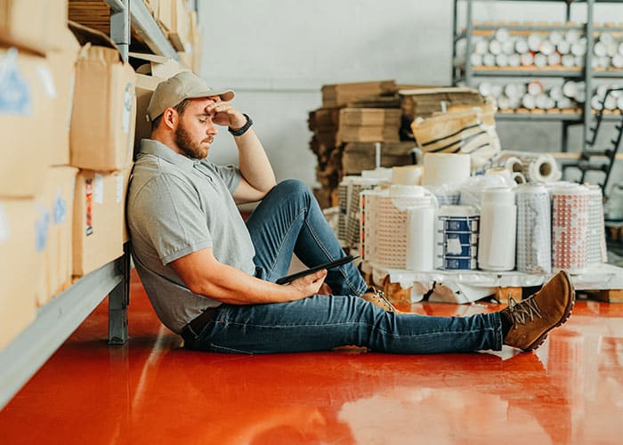 A man sitting on the ground in a warehouse.