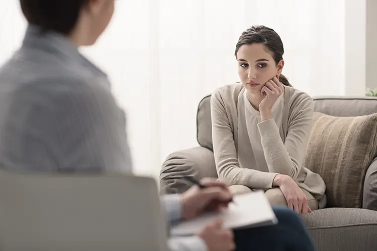 young woman sitting on a couch across from a therapist